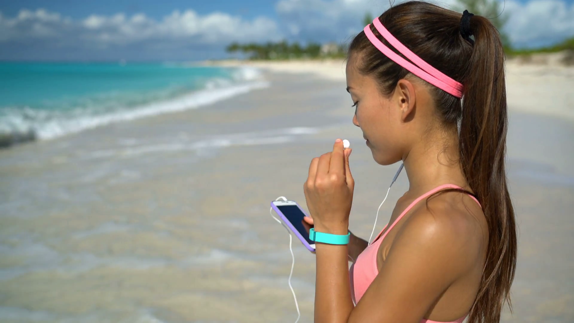 woman-listening-to-music-running-exercising-on-beach-young-woman-putting-earphones-in-ear-getting-ready-to-run-on-sea-shore-female-fitness-girl-training-listening-music-while-jogging-on-sunny-day_hz0ah_-fx_thumbnai